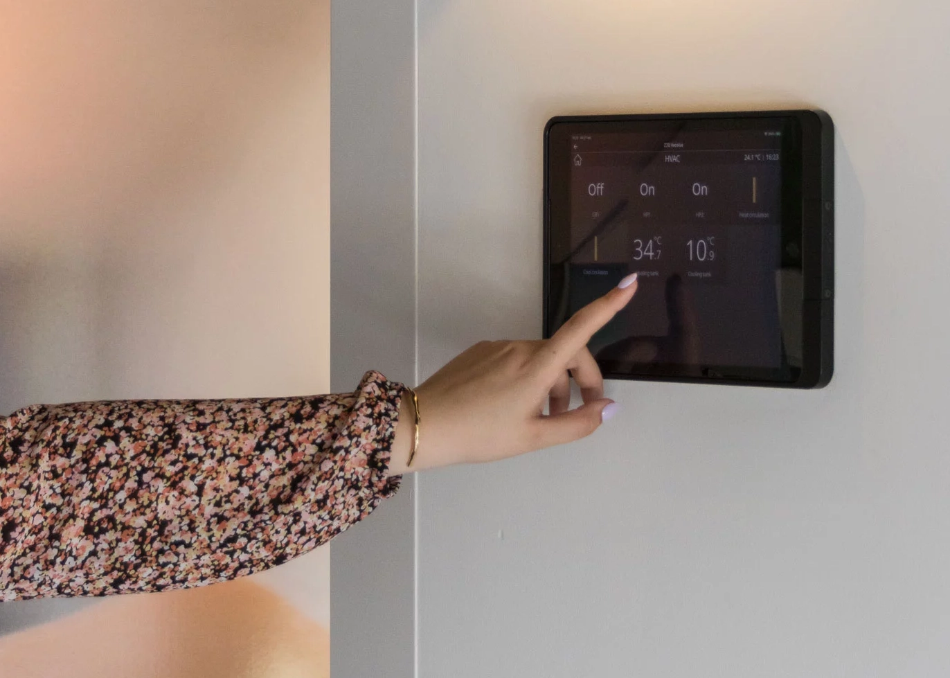 Domotica, vrouwenhand bediend temperatuur via touchscreen aan de muur